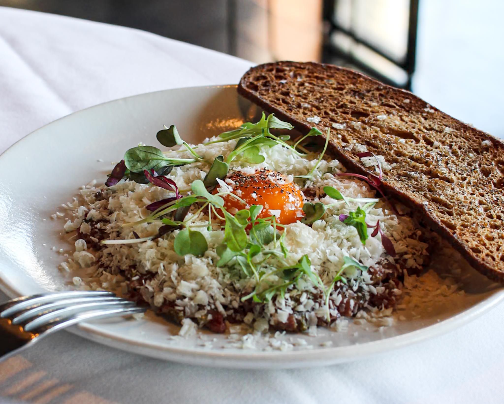 Classic steak tartare topped with Parmesan shavings and a fresh egg yolk at The Grill.