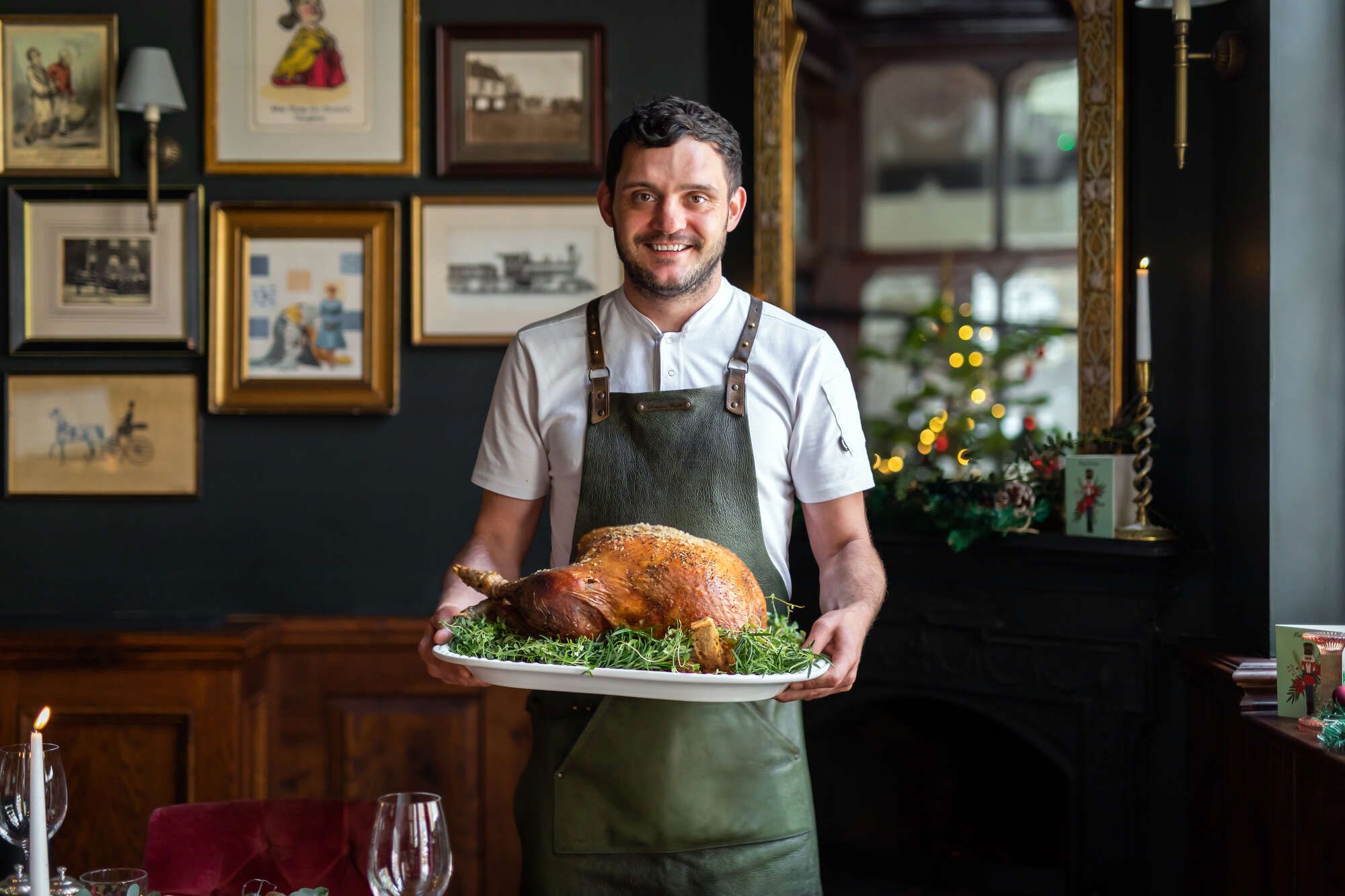 Chef presenting a perfectly roasted Christmas turkey next to a festive Christmas tree at Smiths of Smithfield.