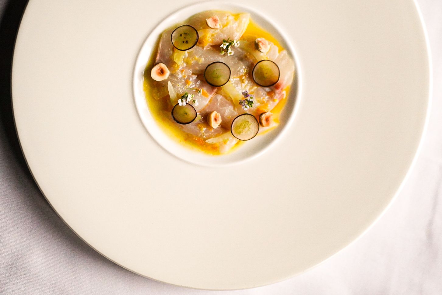 A beautifully presented cured sea bream dish featuring elderflower vinegar, hazelnuts, grapes, and celery from the 7-course tasting menu at The Grill.