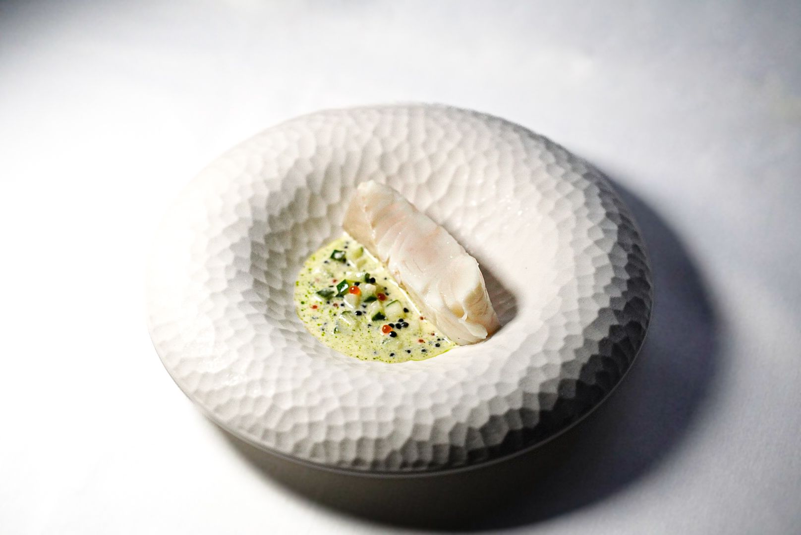 A delicately poached halibut dish served with cucumber, crème fraîche, and Exmoor caviar, featured as a signature course on the 7-course tasting menu at The Grill.